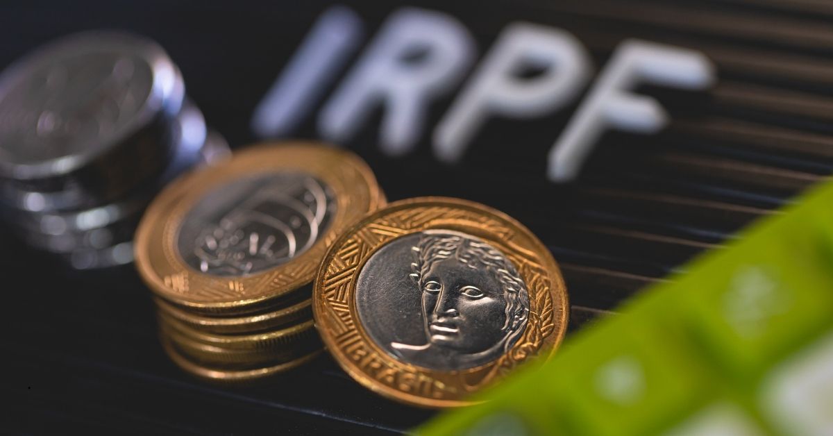 Moedas de Real com o fundo escrito IRPF, representando a isenção do Imposto de Renda de R$ 5.000.